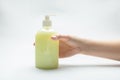 Female hand and bottle with dispenser with yellow liquid soap antiseptic standing on the table on a white background. Horizontal Royalty Free Stock Photo