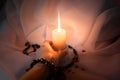 female hand with a bracelet holds a burning candle on a dark natural background. pagan wiccan, slavic traditions. Witchcraft,