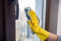 A female hand in bright yellow rubber gloves washes. cleaning the window with a soft rag Royalty Free Stock Photo