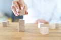 Female hand builds tower from wooden cubes