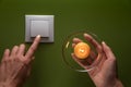 Female hand with burning candle and female finger turns of light switch on the green background. International Day of Energy Savin Royalty Free Stock Photo