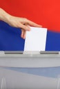 Female hand casts ballot paper in the ballot box.