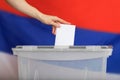 Female hand casts ballot paper in the ballot box.