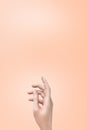 female hand of a Caucasian girl on a gentle background of peach fuzz, trend color of the year 2024. Display for