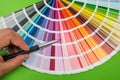 Female hand chooses color in palette swatches. Rainbow colors catalog  on green Royalty Free Stock Photo