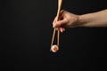 Female hand with chopsticks hold sushi roll on background. Japanese food Royalty Free Stock Photo