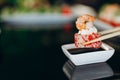 Female hand with chopsticks holds sushi roll, on black background Royalty Free Stock Photo