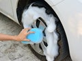 Female hand is cleaning car tire with blue sponge Royalty Free Stock Photo