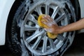 Female hand is cleaning car tire with sponge Royalty Free Stock Photo