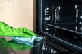 Female hand cleaning surface inside microwave oven with rag