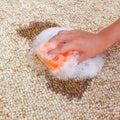 Female hand cleans the carpet with a sponge and detergent. Coffee spilled on the carpet.