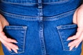 Female hand climbs into the pocket of jeans on the ass