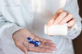 Female hand close up holding a medicine, elderly woman hands with pill on spilling pills out of bottle Royalty Free Stock Photo