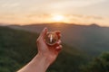 Female hand with compass in mountains at sunrise, pov.