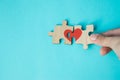 Female hand connecting puzzle with drawn red heart on blue background. Love concept. St. Valentine day. Reconciliation. Reunion Royalty Free Stock Photo