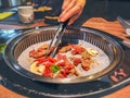 Female hand cooking korean bulgogi griller beef in a bbq grill on restaurant table
