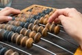 Female hand counting on ancient retro old abacus, moving beads on a wooden background, copy of space, close-up Royalty Free Stock Photo