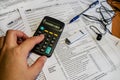 Female hand counts on a calculator. Tax forms 1040, flash drive and pen