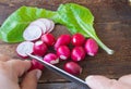 Female hand cuts the radish salad on a wooden Board