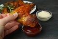 Female hand dipping baked chicken wing into sauce, close up Royalty Free Stock Photo