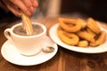 Female hand dipping churro into hot chocolate