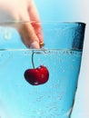 Female hand dips ripe cherry in a glass with water