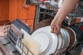 Female hand and dirty plates in dishwasher. Housework concept Royalty Free Stock Photo