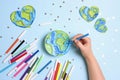 Female hand draws planet Earth with multicolored felt-tip pens on on a blue background. Royalty Free Stock Photo