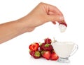 Female hand dunked strawberry into cup with cream