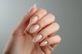 Female hand with elegant colors manicure on neutral background. Beautiful nude manicure on long almond shaped nails