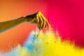 Female hand and explosion of colored, neoned powder on pink studio background with copy space. Magazine cover, wallpaper