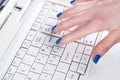 Female hand finger with blue nails press button on white keyboard Royalty Free Stock Photo