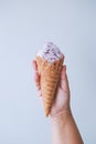 Female hand fingers hold a waffle cone with ice cream