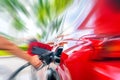 Female Hand with fuel pistol and red car with motion blur effect Royalty Free Stock Photo