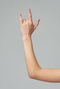 Female hand gesturing rock sign on gray background close up Royalty Free Stock Photo
