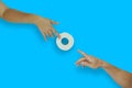 Female hand gives toilet paper roll to male hand on blue background