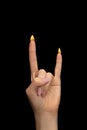 Female hand giving the devil horns gesture with fire on fingers on a black background. Hard rock horns sign with fire on fingers Royalty Free Stock Photo