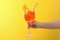 Female hand with glass aperol spritz cocktail on yellow background Royalty Free Stock Photo