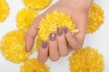 Female hand with glitter beige nail design. Beige nail polish manicure. Woman hand hold yellow orchid flower Royalty Free Stock Photo