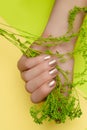 Female hand with gold nail design. Golden nail polish manicured hand. Female hand on green yellow background