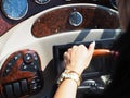 A female hand with a gold watch holds the steering wheel located on the dashboard of a cruise yacht Royalty Free Stock Photo