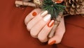 Female hand with golden Christmas nail design. Red and gold nail polish manicure. Female hand hold New Year decoration