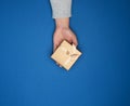 Female hand in a gray sweater holds a closed square cardboard gift box with a bow Royalty Free Stock Photo
