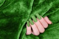 Female hand with green nail design. Mate green nail polish manicure. Female model hand on green fluffy fabric
