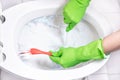 Female hand in rubber glove cleaning toilet bowl Royalty Free Stock Photo