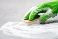 Gloved hand cleaning floor with sponge and detergent foam, closeup Royalty Free Stock Photo