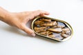 Female hand hold sprats with oil in the open tin can on the white background