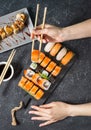 Female hand hold sushi roll with chopsticks on black stone background Royalty Free Stock Photo