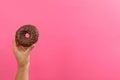 Female hand hold tasty donut on pink background Royalty Free Stock Photo