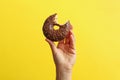 Female hand hold tasty donut on yellow background Royalty Free Stock Photo